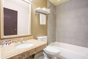 Vanity unit, mirror, shelf with towels, toilet, shower tub