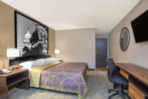 Queen bed, night stands with bedside lamps, telephone and clock, wall mirror, wall mounted TV, desk with office chair, carpet flooring
