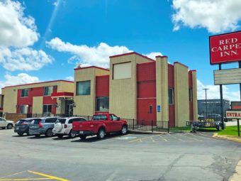 Hotel entrance, signage, two storey building and parking spaces