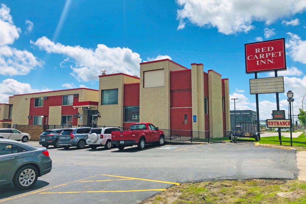 Hotel entrance, signage, two storey building and parking spaces