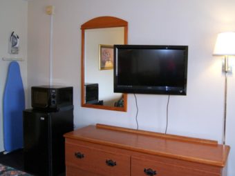 Wall mounted light, wall mounted flat screen tv, large wall mounted mirror, wooden drawer unit, fridge, microwave, wall mounted ironing board and iron