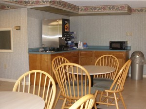 Tables and chairs, breakfast display counter with juice machine, microwave and tiled flooring