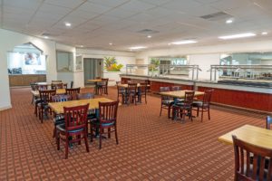 Tables and chairs, food counters, alcove to breakfast display counter, carpet flooring