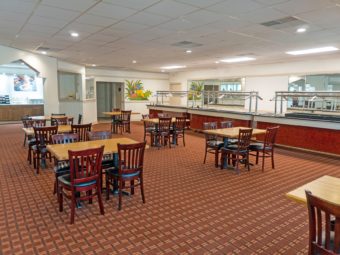Tables and chairs, food counters, alcove to breakfast display counter, carpet flooring