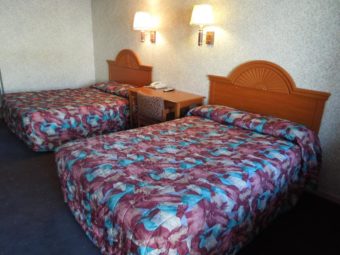 Two double beds, small desk with chair and telephone, wall mounted bedside lights, carpet flooring