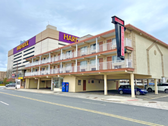 Two story building with exterior room entrances and covered walkways, vending machine and parking spaces