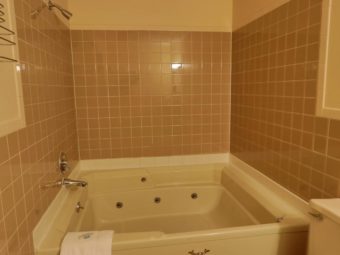 Spa tub with bath mat, tiled walls, wall mounted towel rack
