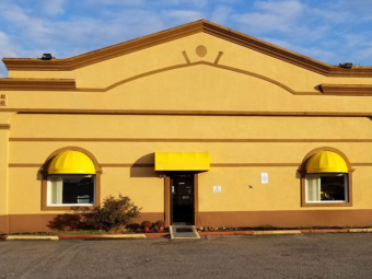 Hotel entrance with small canopy, landscaping with shrubs, ADA Accessible ramp