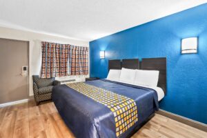 King bed, night stand, wall bedside lights, easy chair, laminate flooring