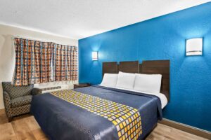 King bed, night stand, wall bedside lights, easy chair, laminate flooring