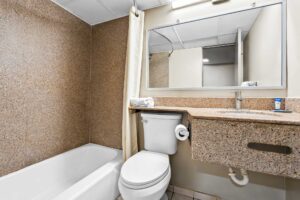 Shower tub with shower curtain, toilet, vanity unit with towel, mirror, tiled flooring