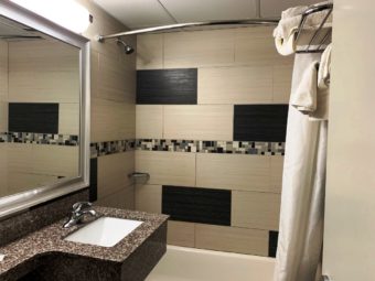 Shower tub with shower curtail, wall mounted towel rail with towels, vanity unit with sink, large wall mounted mirror