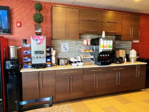 Water dispenser, breakfast display counter with coffee and juice machines, toaster, breakfast pastries display case, cereal dispenser and tiled flooring
