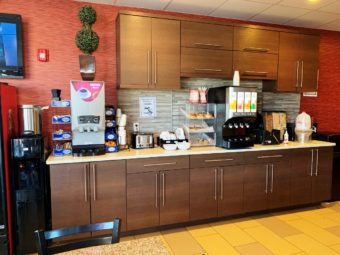Water dispenser, breakfast display counter with coffee and juice machines, toaster, breakfast pastries display case, cereal dispenser and tiled flooring
