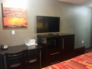 Table with two chairs, telephone and ice bucket, wall mounted art, wall mounted flat screen tv, wooden unit with microwave