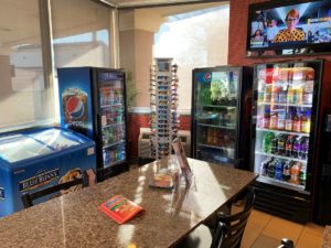 Ice cream cabinet, chilled drinks cabinets, sunglasses stand, wall mounted tv, tables and chairs, drinks vending machine, tiled flooring