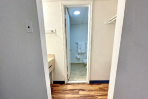 Vanity unit, hanging rail, laminate flooring, doorway to bathroom, towel rail with towels, tiled flooring