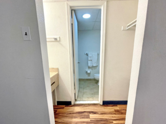 Vanity unit, hanginging rail, laminate flooring, doorway to bathroom, towel rail with towels, tiled flooring