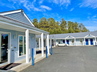 Hotel entrance, one story building with exrior room entrances, covered walkways, parking spaces