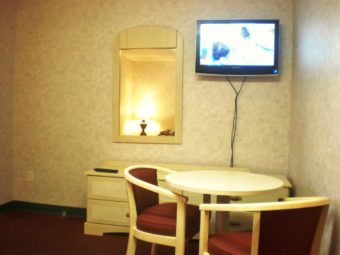 Small table with two chairs, wooden drawer unit, wall mounted mirror, wall mounted flat screen tv, carpet flooring