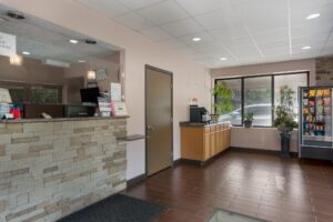 guest check in desk, counter with coffee machine, plants in tubs, vneding machine with snacks, tiled flooring