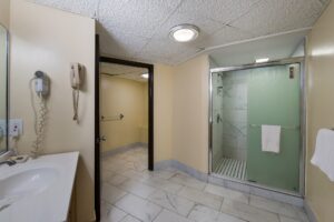 Shower with sliding doors and towel rail with towel, vanity unit, hairdryer, tiled flooring