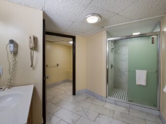 Shower with sliding doors and towel rail with towel, vanity unit, hairdryer, tiled flooring