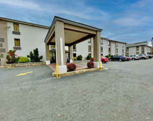 Three story building, drive through canopied hotel entrance, landscaping with small shurbs and flowering shrubs, parking area