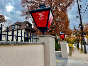 Hotel car parking entrance with branded lights, side walk with trees