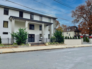 3 story building, hotel entrance, landscaping with small shrubs and trees