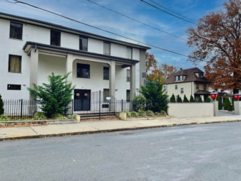 3 story building, hotel entrance, landscaping with small shrubs and trees