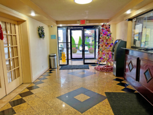 Double entrance doors, decorated christmas tree, ATM machine, trash bin, guest check in desk, tiled flooring with floormats