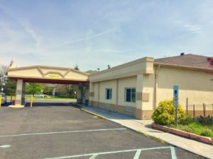 Hotel entrance with canopy, one story building, parking spaces