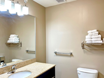 Vanity unit, mirror, towel rail and shelf with towels, toilet