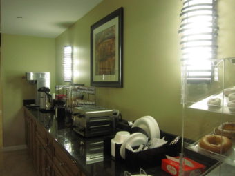 breakfast counter display, coffee pot, toaster, disposable plates and cutlery, breakfast pastried display, wall mounted art