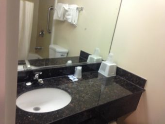 Vanity unit with sink, ice bucket, bathroom amenities, wall mounted mirror, wall mounted towel rail with towels
