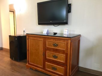 Fridge, wall mounted full length mirror, wooden storage unit, wall mounted flat screen tv, laminate flooring