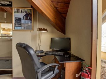Business center with desk and office chair, monitor, desk top computer, keyboard and desk lamp