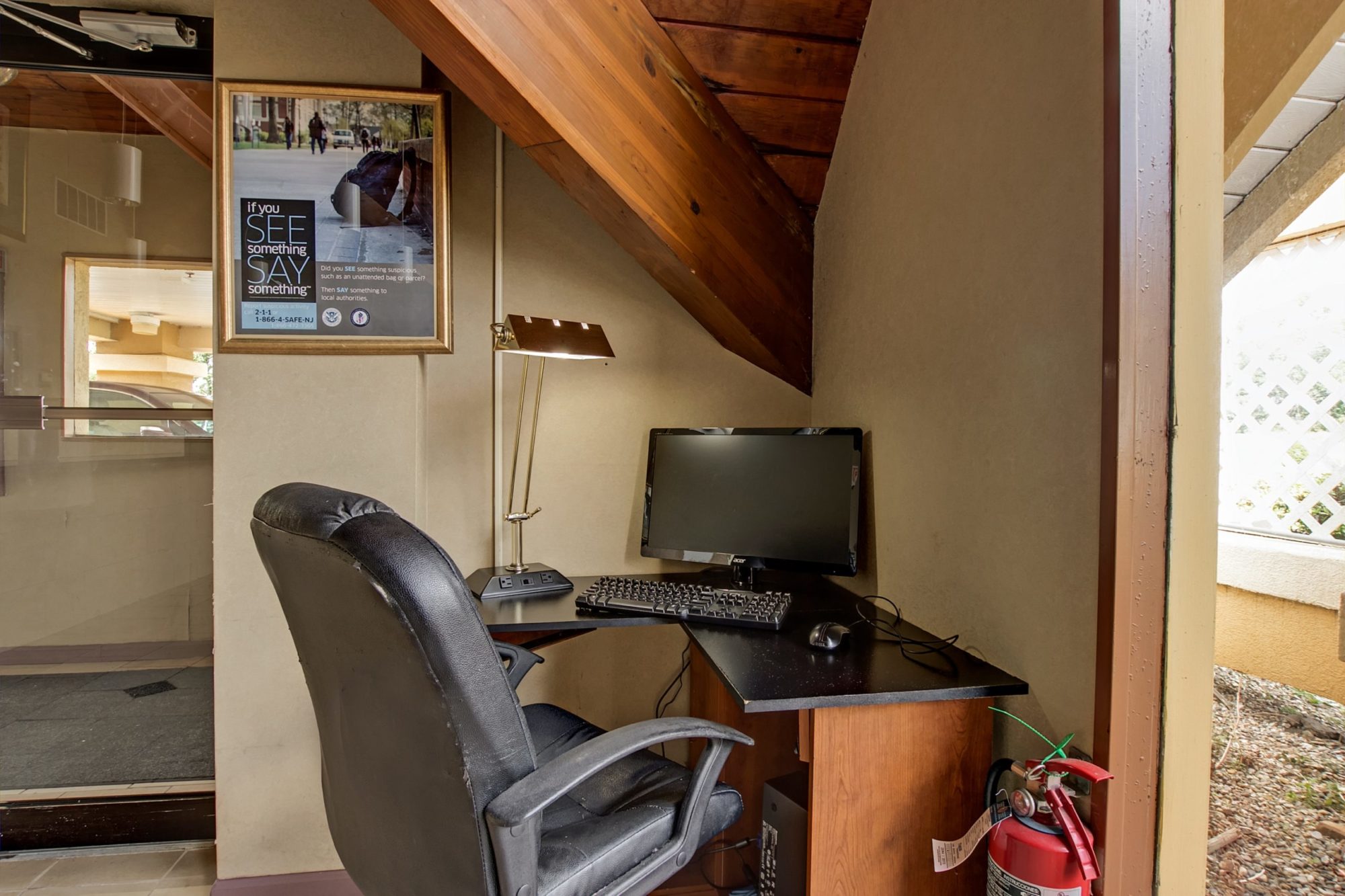 Business center with desk and office chair, monitor, desk top computer, keyboard and desk lamp