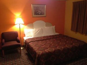 King bed wall mounted art, floor lamp, easy chair, carpet flooring
