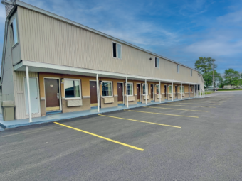 two story building with exterior room entrances with covered walkway, parking spaces