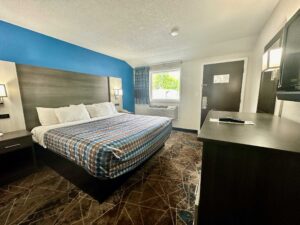 King bed, night stands with telephone, bedside wall lights, mirror, wooden drawer unit, wall mounted TV, carpet flooring