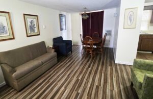 Art images, sofa, easy chairs, table and chairs,, archway to kitchen area, laminate flooring