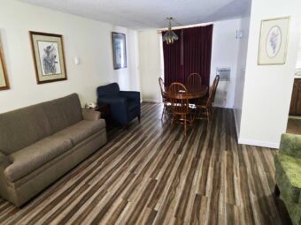 Art images, sofa, easy chairs, table and chairs,, archway to kitchen area, laminate flooring