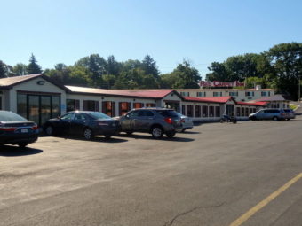 One story building, parking spaces, large trees in the background