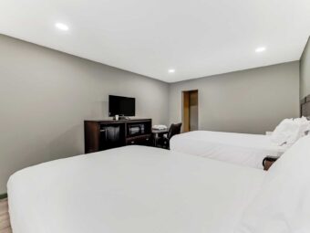 Two double beds, night stand with telephone, desk with chair, wooden unit with TV, laminate flooring