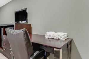 Desk with chair and towels, wooden unit with microwave, fridge and TV