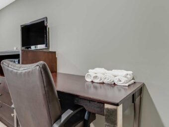 Desk with chair and towels, wooden unit with microwave, fridge and TV