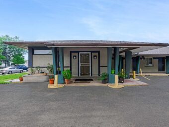 Hotel entrance, plants in tubs, parking spaces, grassy area