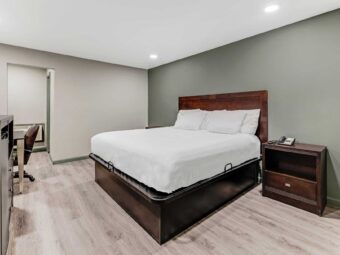 King bed, night stands with telephone, wooden unit with fridge, desk with chair, laminate flooring